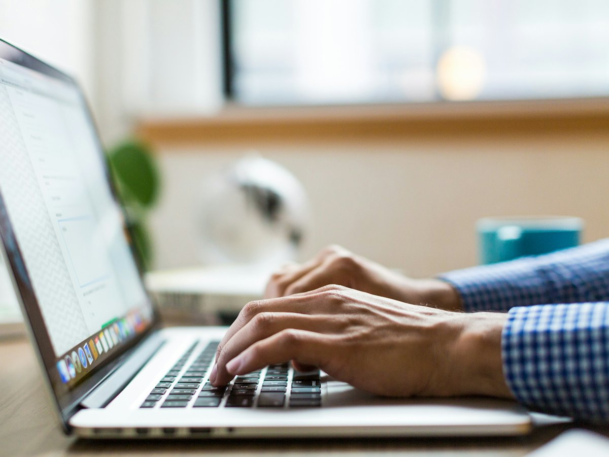 Hands typing on a laptop keyboard