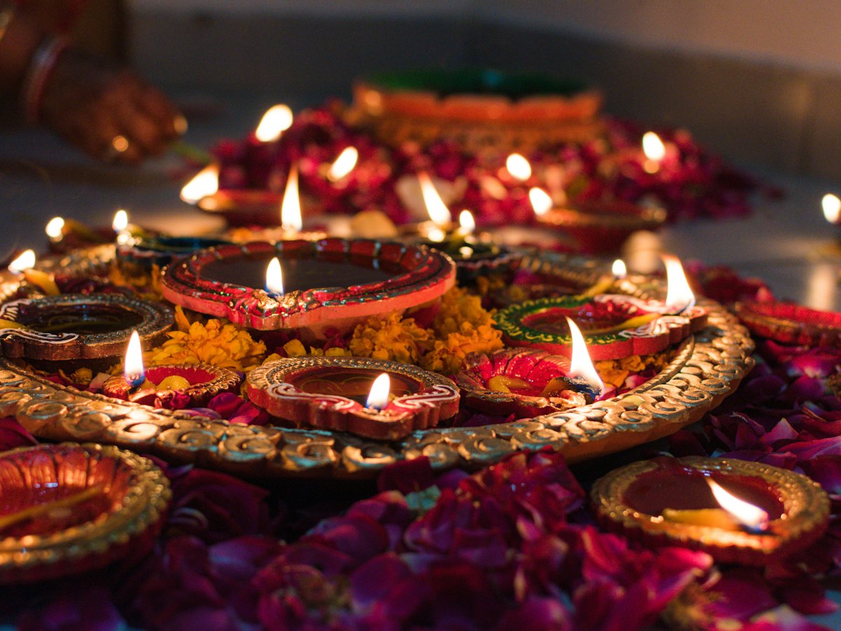 Lit diyas on a tray with flower petals for Diwali