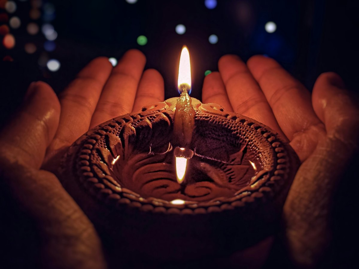 Hands holding a lit diya
