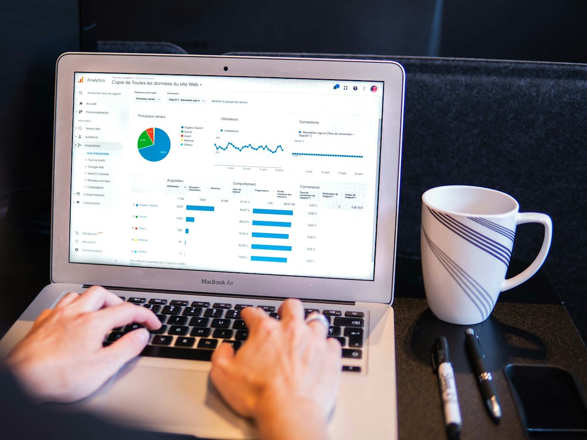 Hands typing on a laptop showing website analytics charts