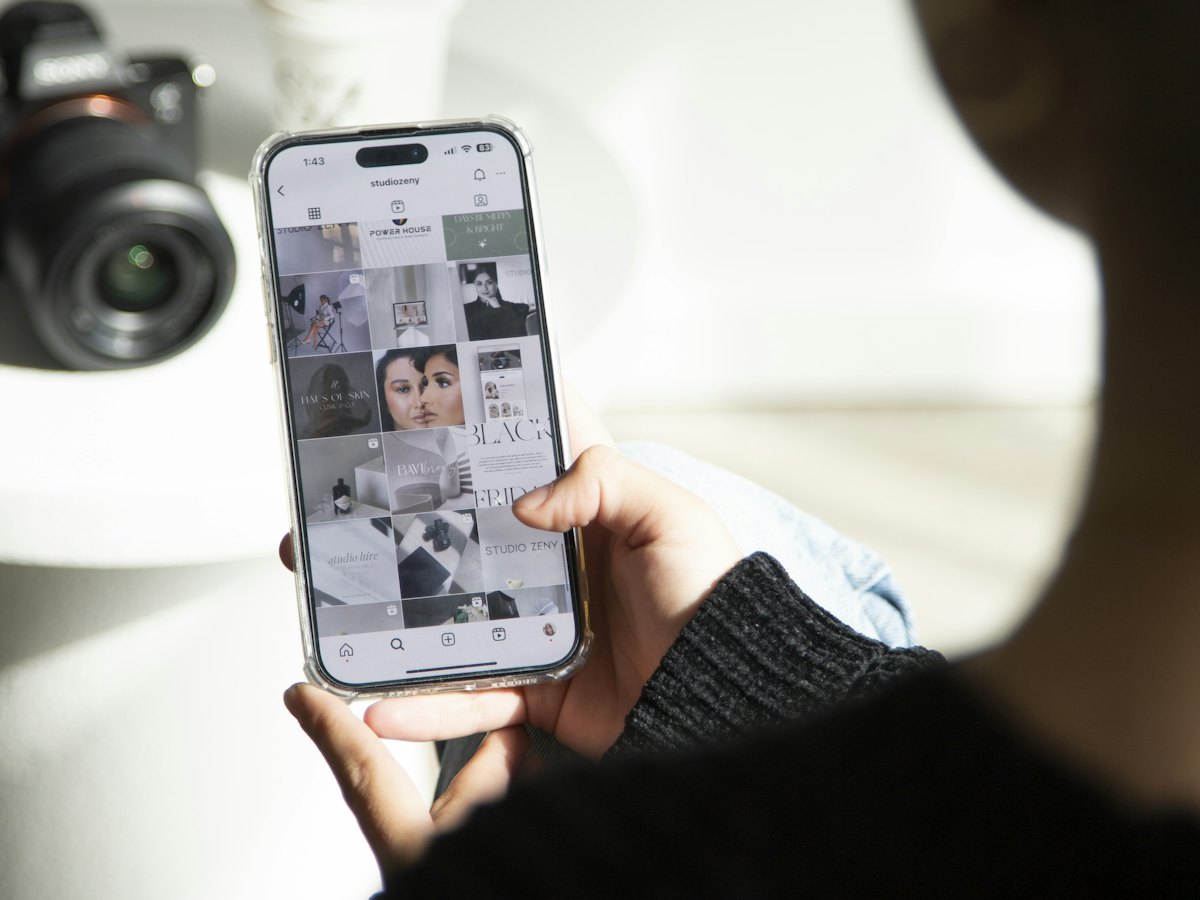 Hand holding a phone showing a photo grid