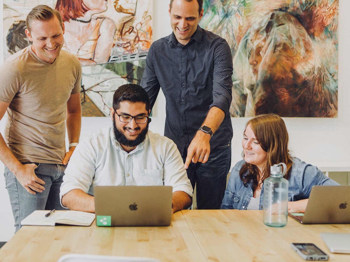 Coworkers smiling around a laptop